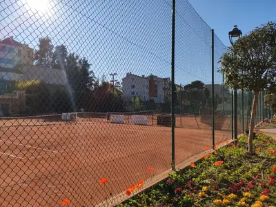 a tennis court with a fence and flowers at Très beau T2 dans parc montfleury ,proche centre ,au calme 44 bd Montfleury in Cannes