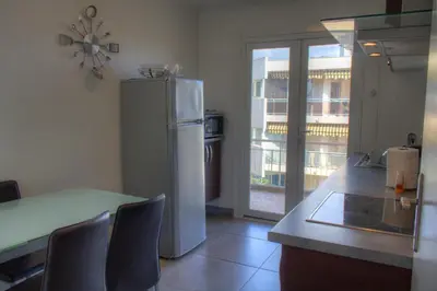 a kitchen with a refrigerator and a table with chairs at BEL APPARTEMENT PROCHE PLAGE ET CENTRE VILLE in Cannes