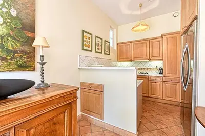 a kitchen with wooden cabinets and a white refrigerator at L'ORANGER maison pittoresque et confortable proche des plages, Croisette et centre-ville in Cannes