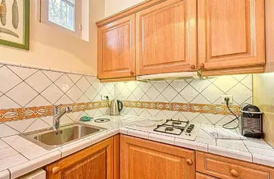 a kitchen with wooden cabinets and a sink at L'ORANGER maison pittoresque et confortable proche des plages, Croisette et centre-ville in Cannes