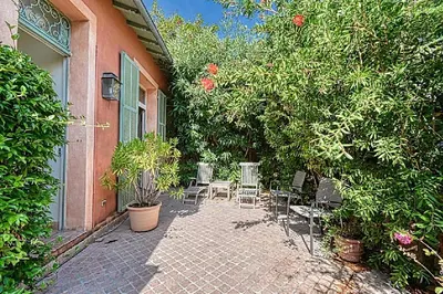a patio with tables and chairs in front of a house at L'ORANGER maison pittoresque et confortable proche des plages, Croisette et centre-ville in Cannes