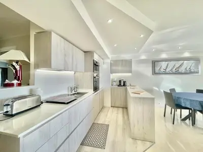 a kitchen with white cabinets and a blue table at Vezelay, by Welcome to Cannes in Cannes
