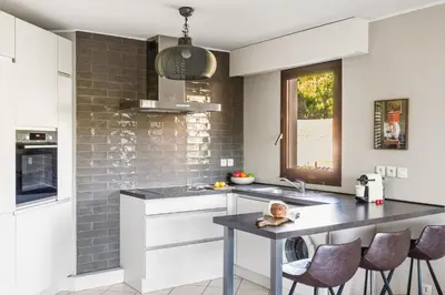 a kitchen with white cabinets and a black counter top at Vivre Cannes l Parking l Balcony l 15min to La Croisette in Cannes
