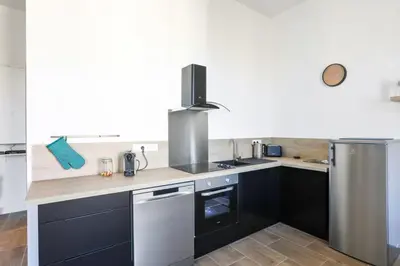 a kitchen with black cabinets and a counter top at Appartement Carnot - Welkeys in Cannes