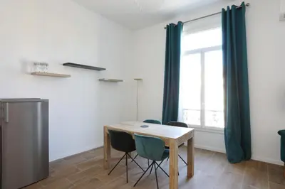 a dining room with a table and chairs and a window at Appartement Carnot - Welkeys in Cannes