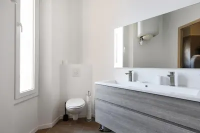 a white bathroom with a sink and a toilet at Appartement Carnot - Welkeys in Cannes