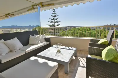 a living room with a couch and a table on a balcony at Close to downtown Cannes swimming pool and sea view in Cannes