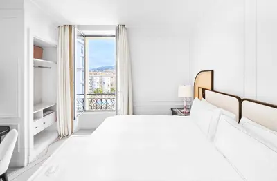 a white bedroom with a large bed and a window at Carlton Cannes, a Regent Hotel in Cannes