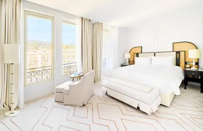 a bedroom with a white bed and a large window at Carlton Cannes, a Regent Hotel in Cannes