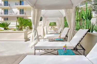 a row of white beds on a patio with plants at Carlton Cannes, a Regent Hotel in Cannes