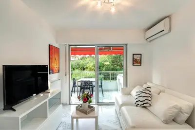 a living room with a white couch and a television at Appartement 2 pièces au calme proche Martinez avec parking privé in Cannes