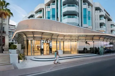 a woman walking past a building with a large building at JW Marriott Cannes in Cannes