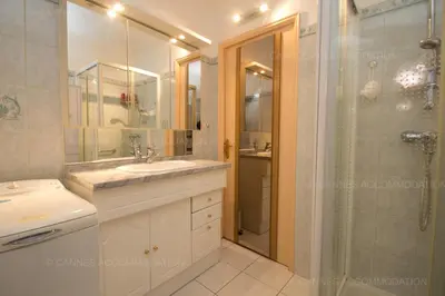 a white bathroom with a shower and a sink and a shower at Jonquille in Cannes