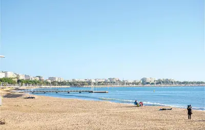 a beach with people sitting on the sand and the water at Nice Apartment In Le Cannet With Wifi in Le Cannet