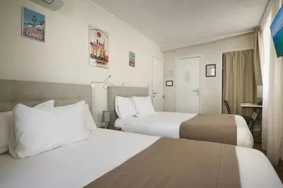 a hotel room with two beds and a table at Hotel des Congrès et Festivals in Cannes