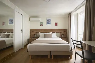 a bedroom with a bed and a desk with a chair at Hotel des Congrès et Festivals in Cannes