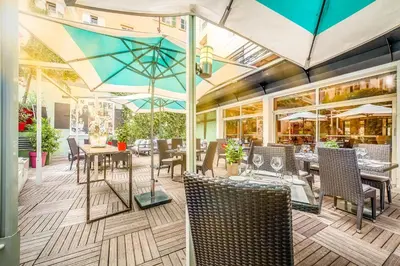 a restaurant with tables and chairs and umbrellas at Hôtel Montaigne & Spa - Cannes Centre in Cannes