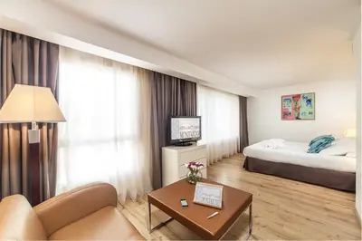 a hotel room with a bed and a couch at Hôtel Montaigne & Spa - Cannes Centre in Cannes