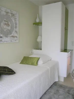 a bedroom with a white bed with a green pillow at Modern two bedroom apartment with two bathrooms, just behind the CARLTON in Cannes