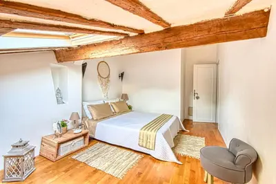 a white bedroom with a bed and a chair at LE BOISE merveilleux duplex rustique, excellent emplacement à quelques pas du Palais in Cannes