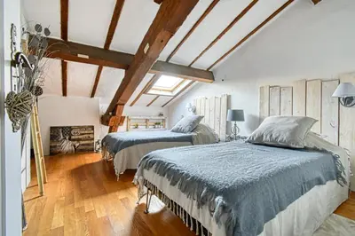 two beds in a bedroom with wooden ceilings and wooden floors at LE BOISE merveilleux duplex rustique, excellent emplacement à quelques pas du Palais in Cannes