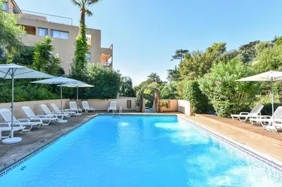 a swimming pool with lounge chairs and umbrellas at Résidence Villa Livia in Cannes
