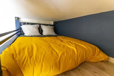 a bed with a yellow comforter in a room at Relaxhome - Hypercentre - Clim - Netflix in Cannes