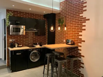 a kitchen with a washer and a brick wall at Relaxhome - Hypercentre - Clim - Netflix in Cannes