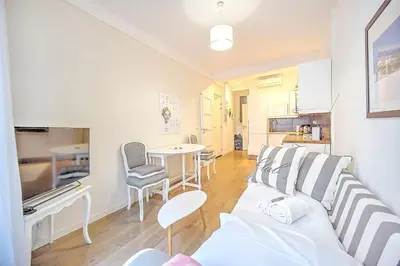 a living room with a white couch and a kitchen at Cannes Carré d'Or Cozy 1 BR balcony, Croisette Palais 2 mn by Olam Properties in Cannes