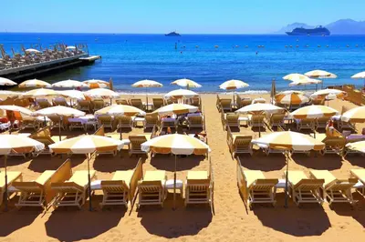 a bunch of chairs and umbrellas on a beach at Cannes Carré d'Or Cozy 1 BR balcony, Croisette Palais 2 mn by Olam Properties in Cannes