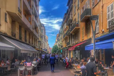 a group of people walking down a street with tables and chairs at Cannes Carré d'Or Cozy 1 BR balcony, Croisette Palais 2 mn by Olam Properties in Cannes