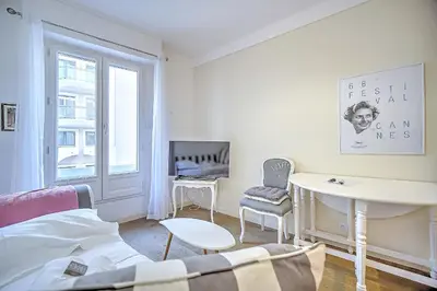a white living room with a table and a window at Cannes Carré d'Or Cozy 1 BR balcony, Croisette Palais 2 mn by Olam Properties in Cannes