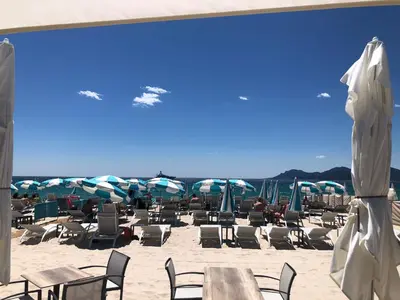a beach with chairs and tables and umbrellas at Cannes Heart of town Cozy bright warm & sunny studio by Olam Properties in Cannes
