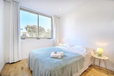 a white bedroom with a bed and a window at Cannes Heart of town Cozy bright warm & sunny studio by Olam Properties in Cannes