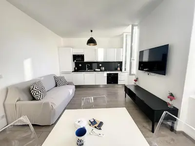 a white living room with a couch and a tv at Cosy 1BR Cannes Gambetta hyper centre - Croisette 1 mn - 4 pers by Olam Properties in Cannes