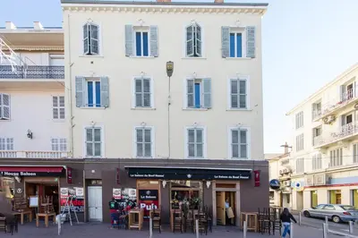 a large white building with blue shutters on a street at Cosy 1BR Cannes Gambetta hyper centre - Croisette 1 mn - 4 pers by Olam Properties in Cannes