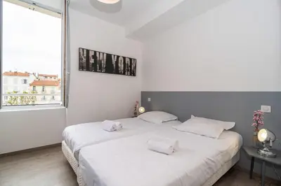 a white bedroom with two beds and a window at Brand new 2 BR Gambetta Fully Renovated 2021- 5 mns Palais by Olam Properties in Cannes
