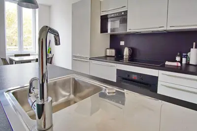 a kitchen with a stainless steel sink and white cabinets at Brand new 2 BR Gambetta Fully Renovated 2021- 5 mns Palais by Olam Properties in Cannes