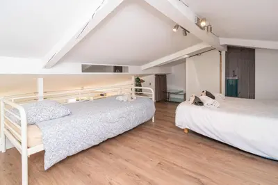 two beds in a bedroom with wooden floors at Cannes Close Centre 2 BR 2 bath mezzanine & balconies Exceptional Rating Ideal Families Easy parking by Olam Properties in Cannes