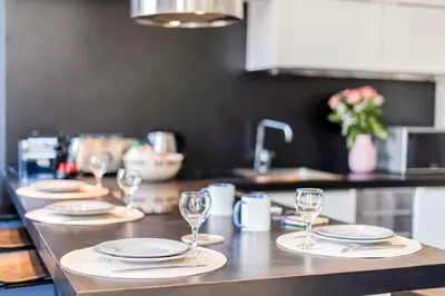 a kitchen counter with plates and wine glasses on it at Heart of Cannes Amazing design apartment Croisette Top Location Best Seller by OIam Properties in Cannes