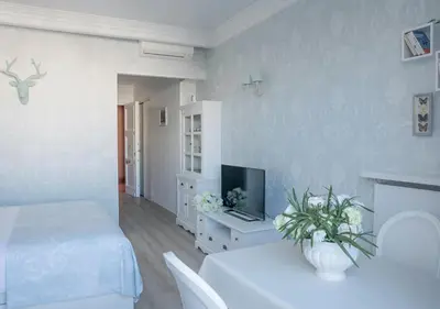 a white room with a bed and a tv at Croisette Palais Miramar Cannes Imperial in Cannes