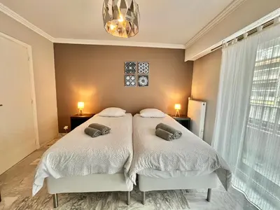 a bedroom with two beds and a chandelier at Branly 2, by Welcome to Cannes in Cannes