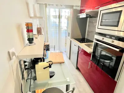 a small kitchen with red cabinets and a microwave at Branly 2, by Welcome to Cannes in Cannes
