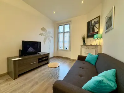 a living room with a couch and a tv at Vénus By SCLS Locations in Cannes