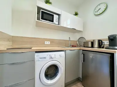 a kitchen with a washing machine and a microwave at Vénus By SCLS Locations in Cannes