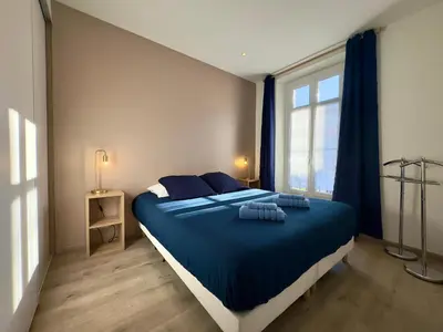a bedroom with a bed with blue sheets and a window at Vénus By SCLS Locations in Cannes