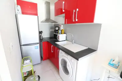 a kitchen with red cabinets and a washing machine at Carré d'Or 1 bedroom 2 mins from Croisette 5 from Palais 243 in Cannes