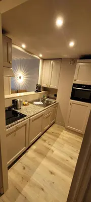 a kitchen with white cabinets and a wooden floor at Villa d'Estelle in Cannes