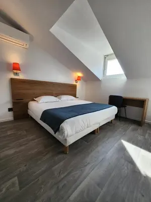a hotel room with two beds and a table at Hôtel Alizé in Cannes