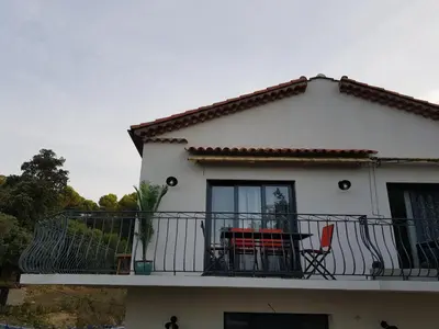a white house with a balcony with a table and chairs at A little Eden in Le Cannet